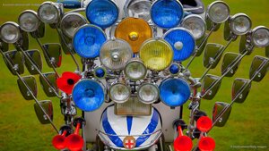 A scooter adorned with multiple mirrors, lights, and air horns