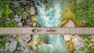Cyclists on a wooden suspension bridge over the Soča River in Slovenia