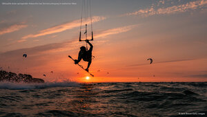 Silhouette eines springenden Kitesurfers bei Sonnenuntergang im baltischen Meer