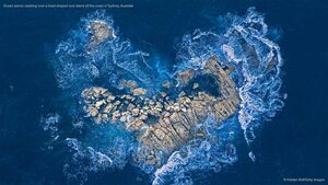 Ocean waves crashing over a heart-shaped rock island off the coast of Sydney, Australia