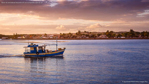 Barco de pescadores flutuando em um rio durante o pôr do sol